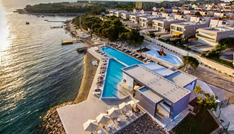 Vue aérienne d'un complexe hôtelier avec piscine et accès à la mer.