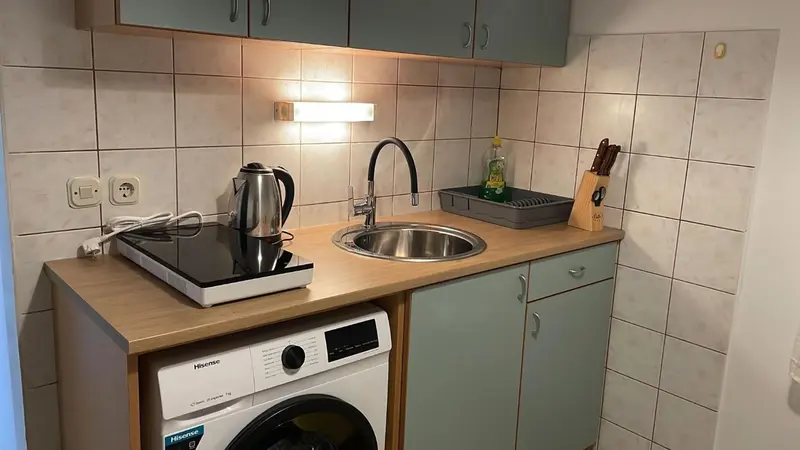 Une kitchenette avec un évier, une plaque de cuisson et un réfrigérateur.