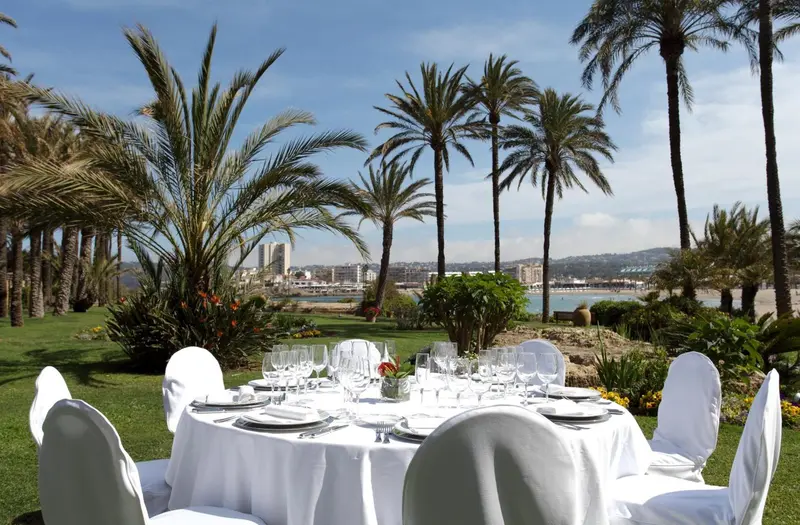 Tables dressées en extérieur avec vue sur la mer et la végétation luxuriante.