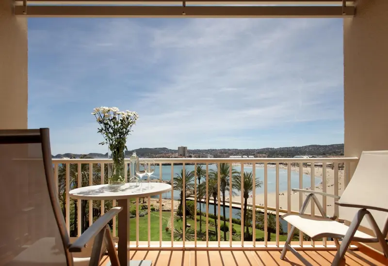 Vue d'une terrasse avec mobilier et vue sur la mer et la végétation.