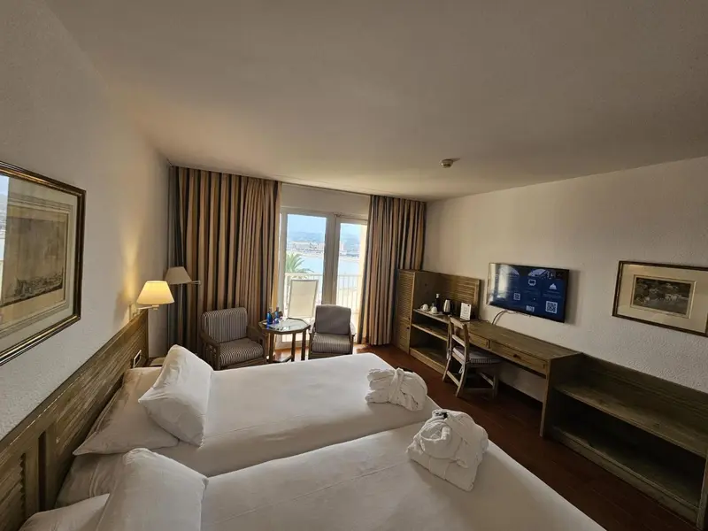 Chambre lumineuse avec lits jumeaux et vue sur la mer.