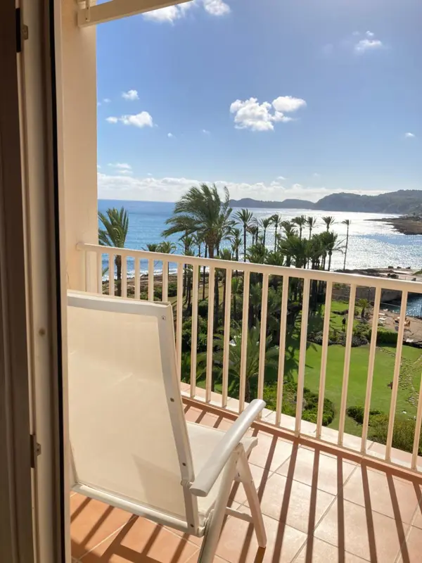 Vue sur la mer depuis un balcon avec un fauteuil blanc.