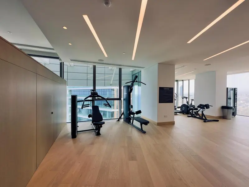 Une salle de sport lumineuse avec des équipements de musculation et une grande baie vitrée.
