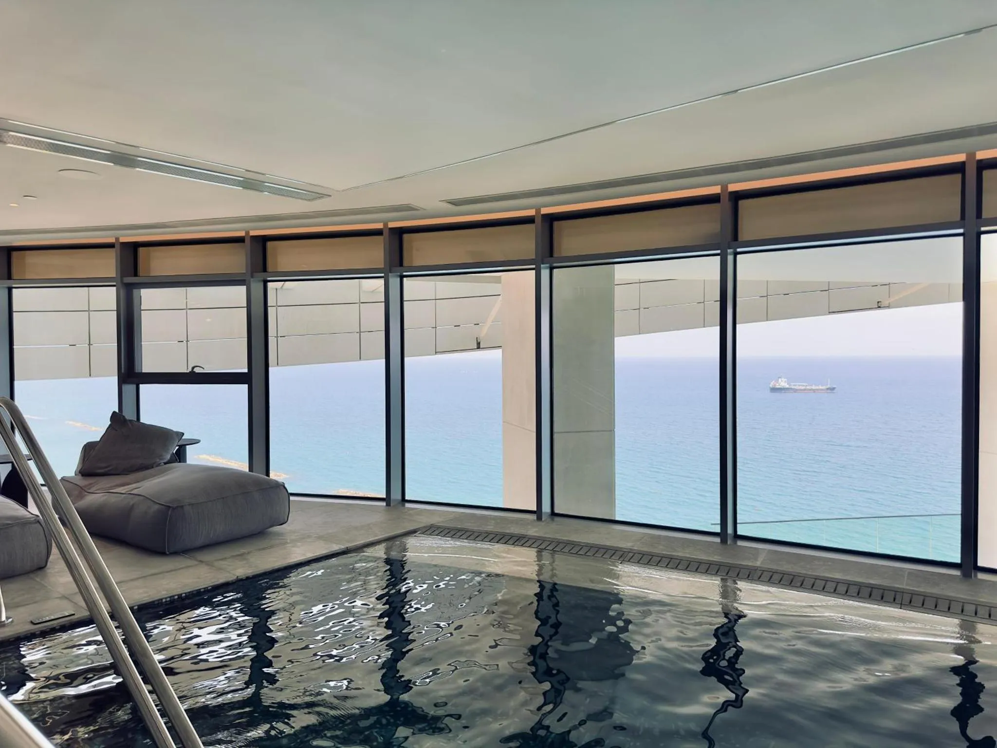 Espace de détente intérieur avec piscine et vue sur la mer.