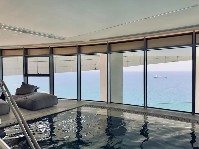 Espace de détente intérieur avec piscine et vue sur la mer.