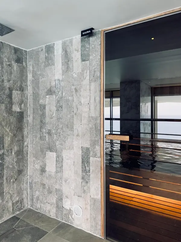 Intérieur d'un sauna avec des murs en pierre et une porte vitrée.