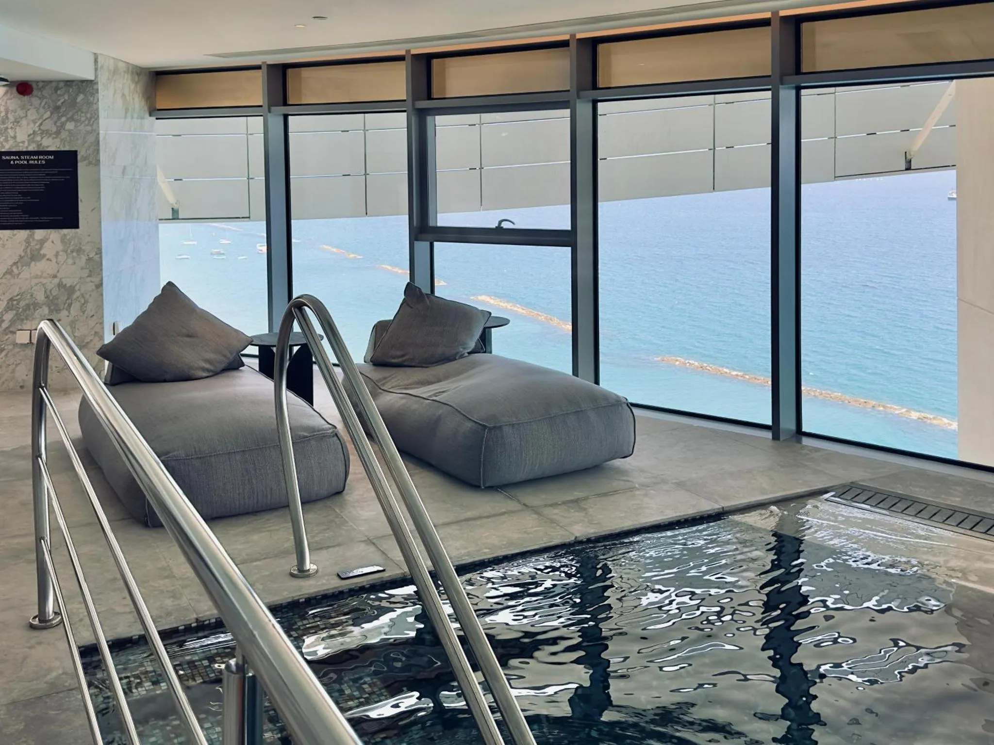 Espace de détente intérieur avec vue sur la mer et piscine.
