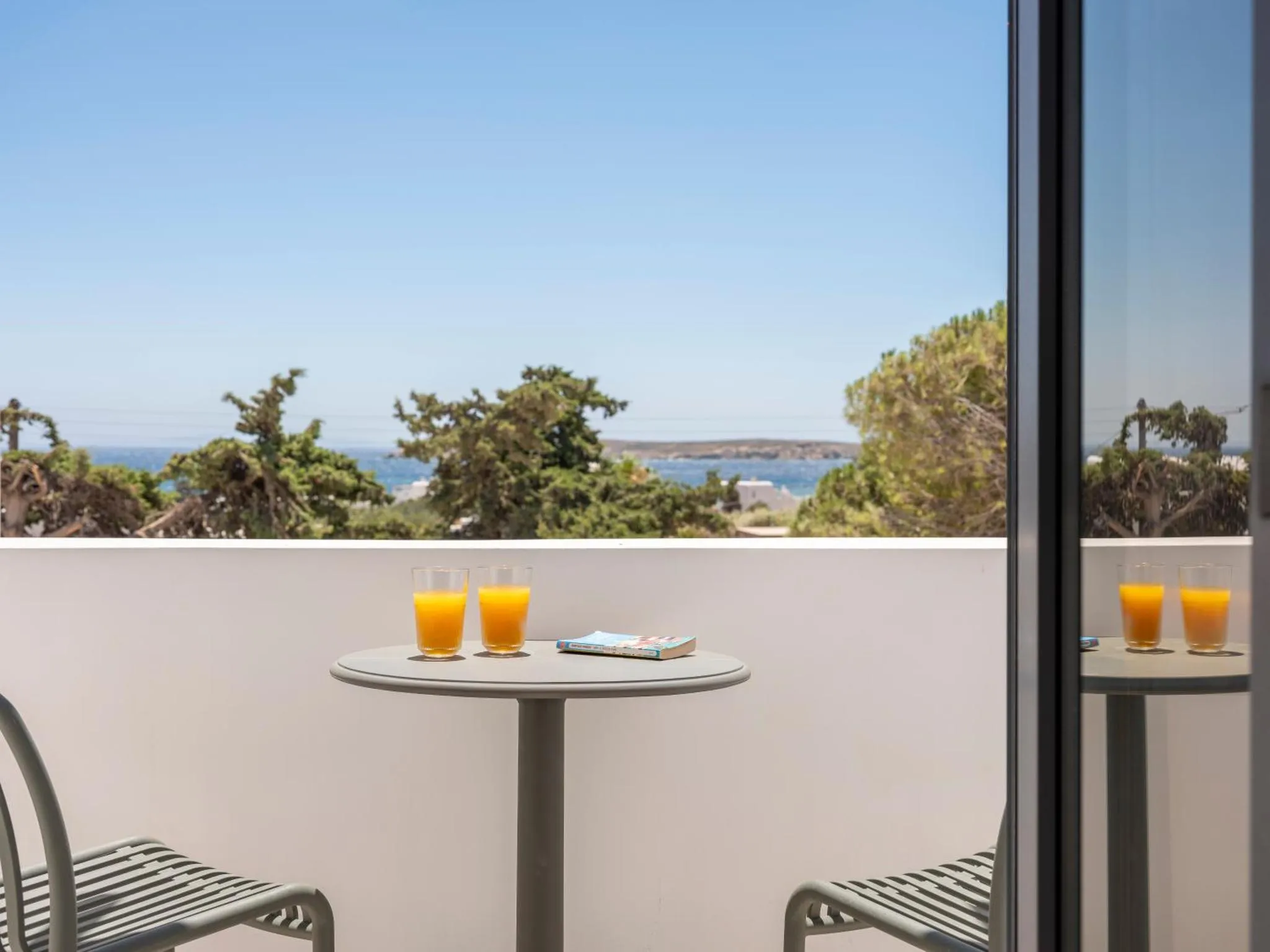 Deux verres de jus d'orange sur une table basse avec vue sur la mer.