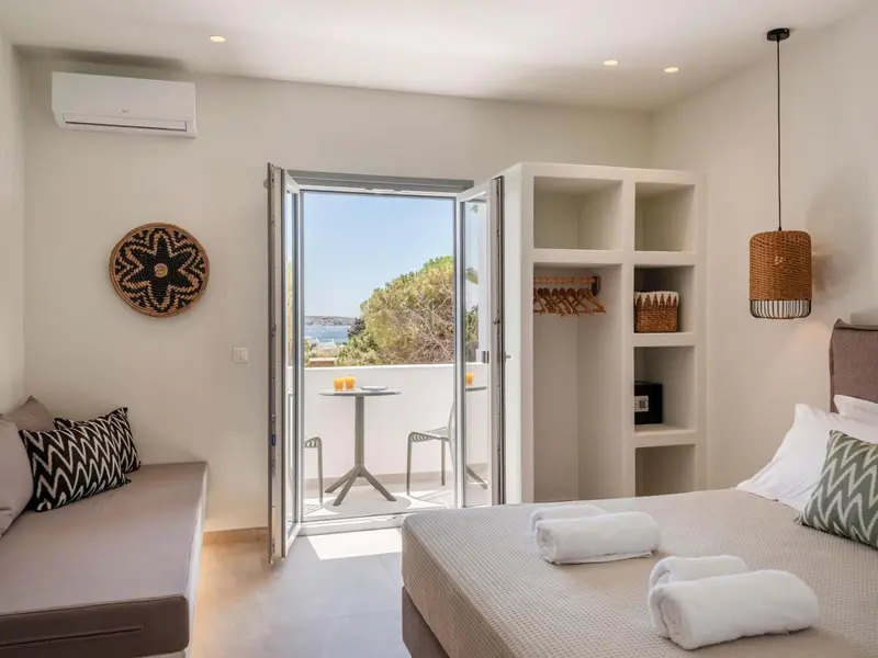 Une chambre lumineuse s'ouvre sur un balcon avec vue sur la mer.