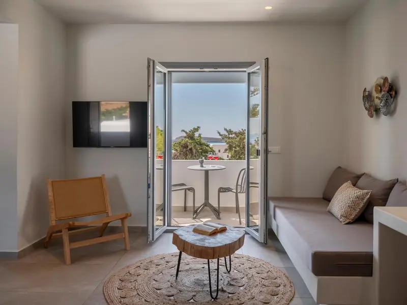Une pièce lumineuse avec un canapé, une télévision et un accès à un balcon.