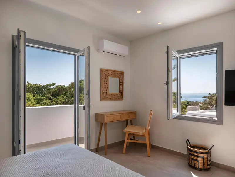 Une chambre lumineuse s'ouvre sur une terrasse avec vue sur la mer.
