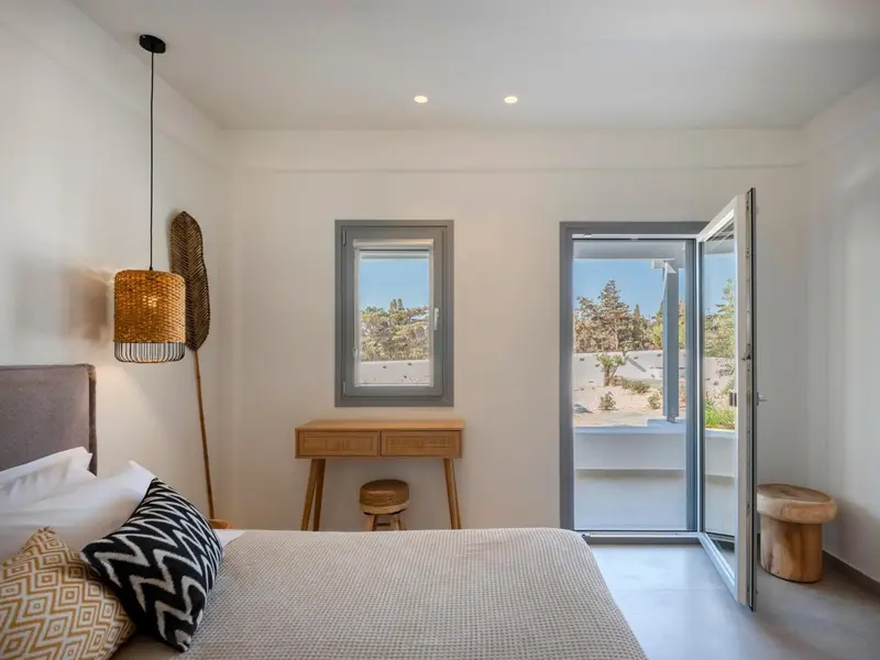 Une chambre lumineuse avec un lit et un bureau donnant sur l'extérieur.