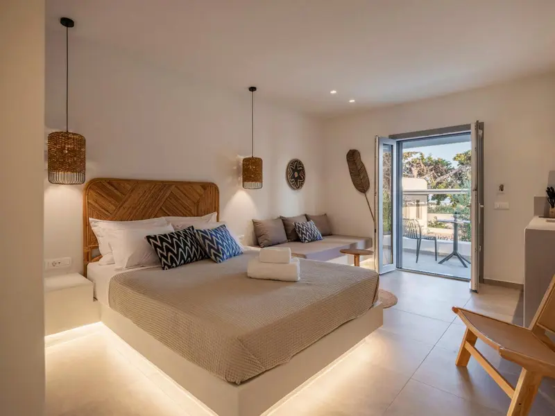 Une chambre lumineuse avec un grand lit et un canapé près d'une baie vitrée.