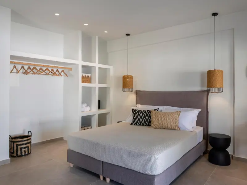 Une chambre lumineuse avec un grand lit et des luminaires suspendus.