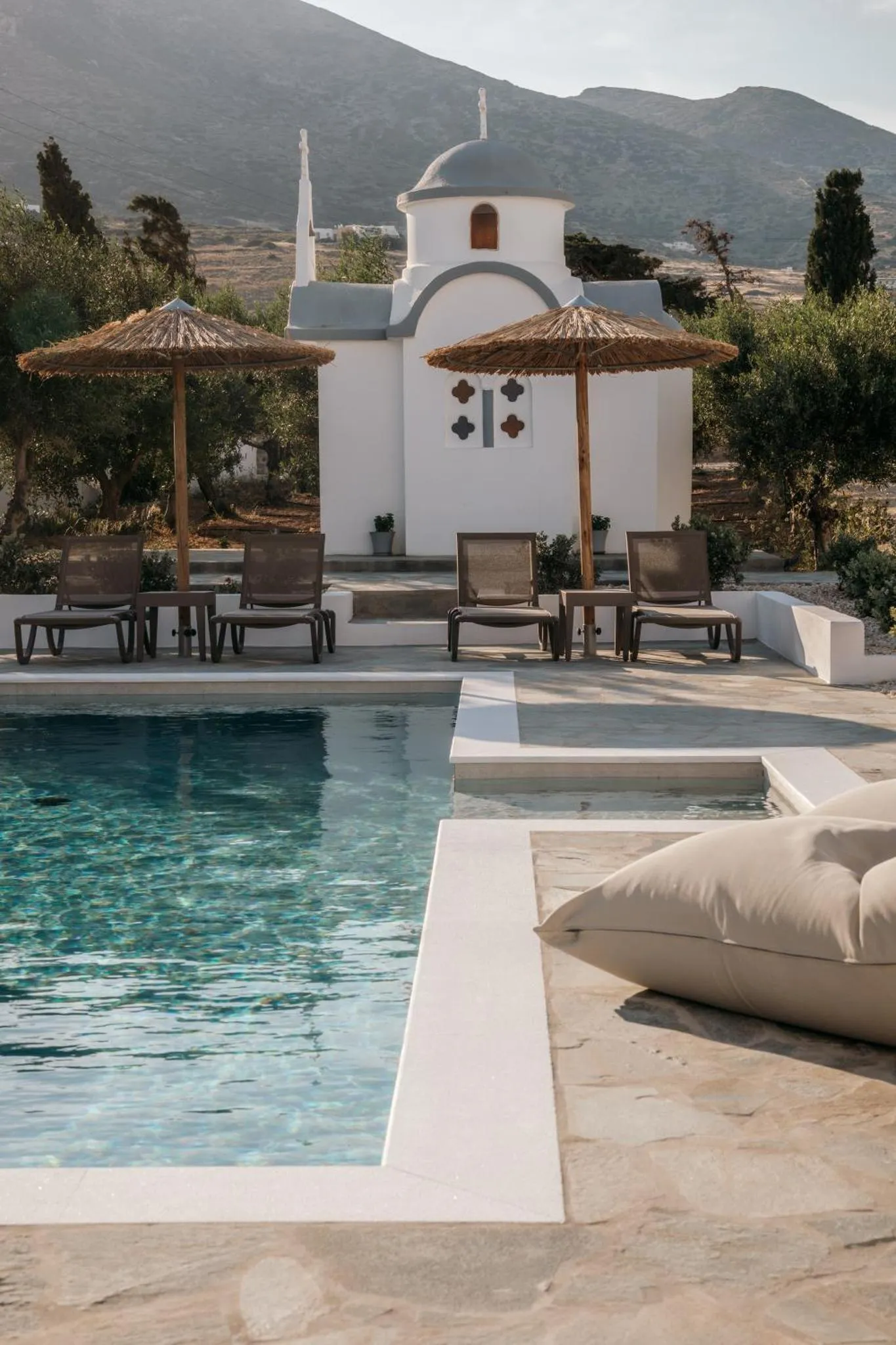 Transats et parasols ombragent une piscine bordée d'une terrasse ensoleillée.