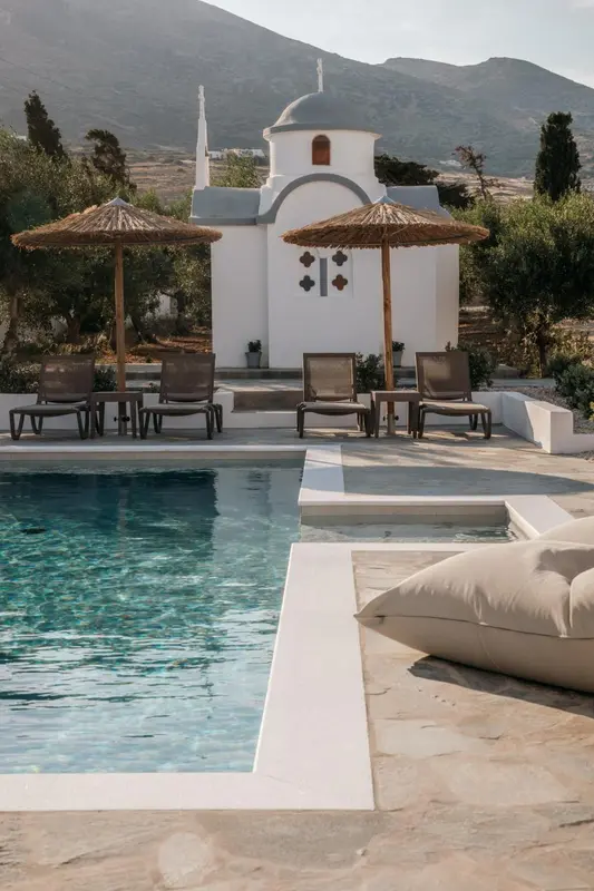Transats et parasols ombragent une piscine bordée d'une terrasse ensoleillée.