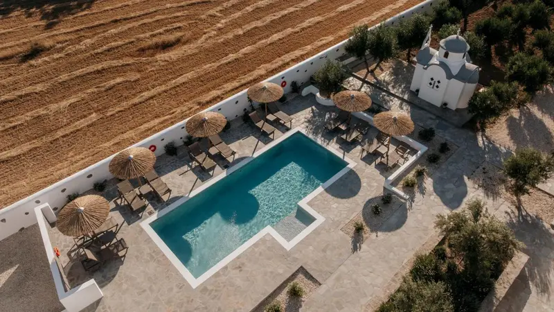 Vue aérienne d'une piscine rectangulaire entourée de chaises longues et de parasols.