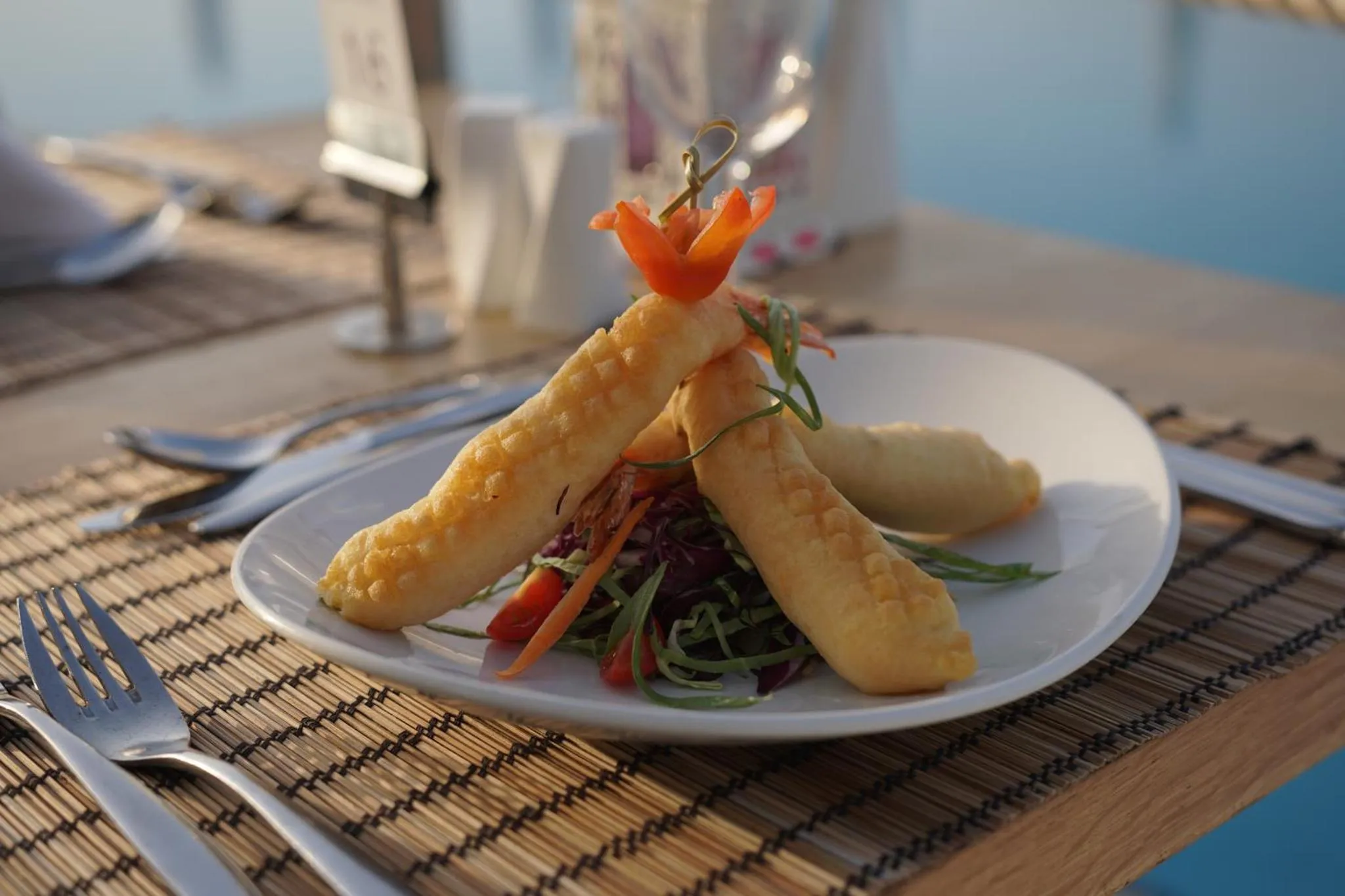 Assiette de beignets de crevettes décorée de légumes et d'une sauce.