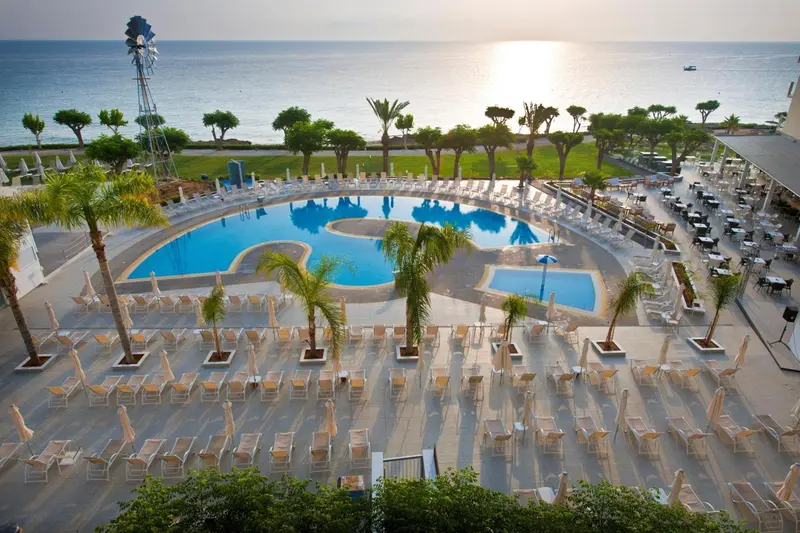 Vue aérienne d'une piscine d'hôtel avec des transats et des parasols.