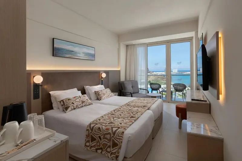 Chambre lumineuse avec un grand lit et une vue sur la mer.