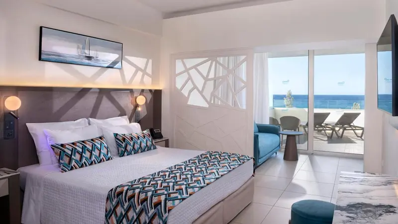 Une chambre lumineuse avec un grand lit et un accès à une terrasse ensoleillée.