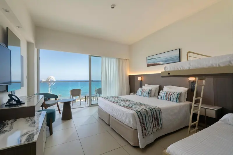 Chambre lumineuse avec vue sur la mer et un lit superposé.