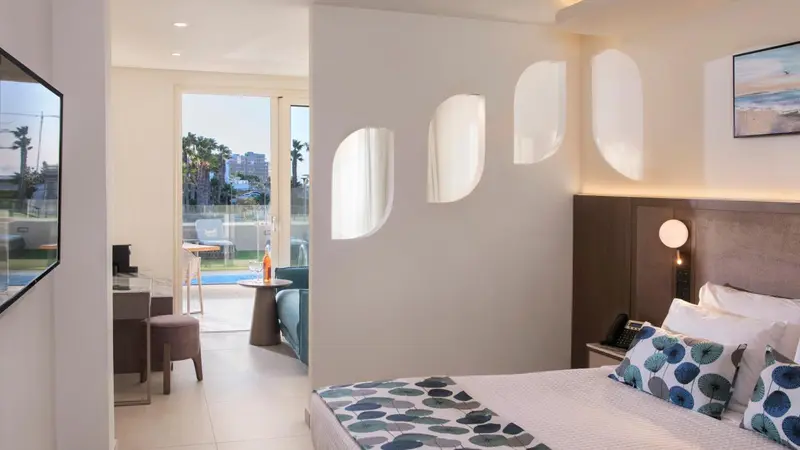 Une chambre lumineuse avec un lit et un espace repas ouvert sur une terrasse.