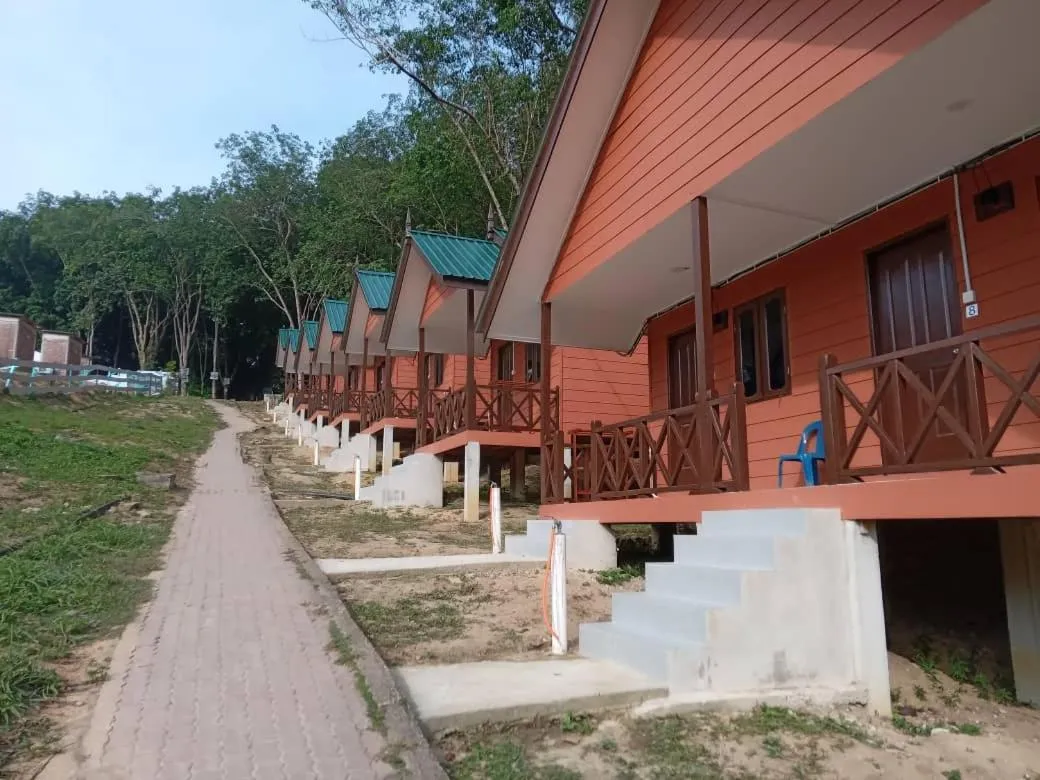 Rangée de bungalows sur pilotis avec terrasse et végétation en arrière-plan.