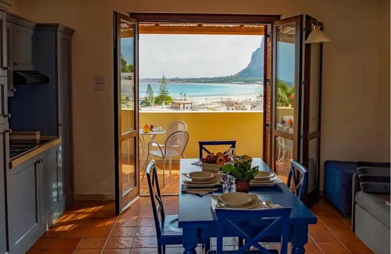 Une table est dressée devant une ouverture sur une vue de mer.