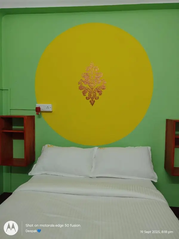 Lit simple avec oreillers blancs dans une chambre aux murs colorés.