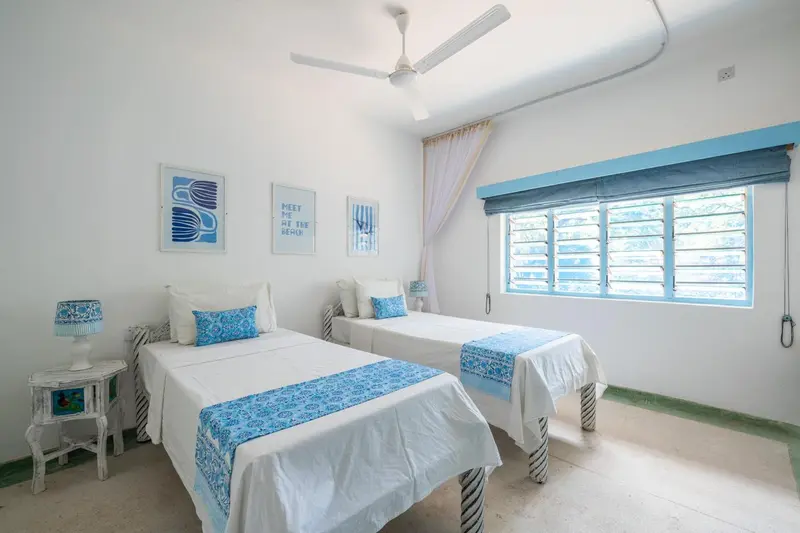 Une chambre lumineuse avec deux lits simples et une décoration marine.