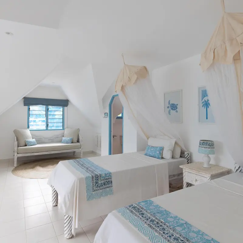 Une vue d'ensemble d'une chambre à coucher avec un lit double, des tables de chevet et un balcon donnant sur la mer.