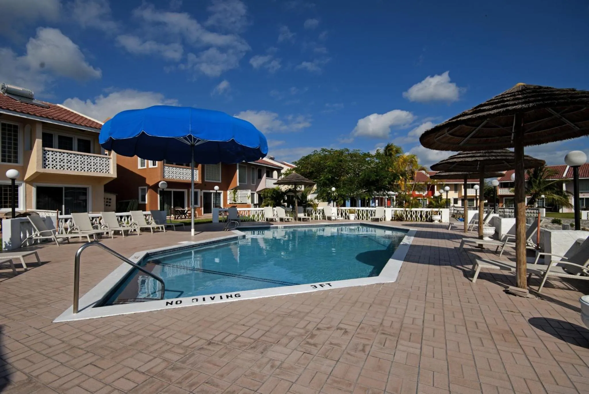 Une piscine rectangulaire bordée de chaises longues et d'ombrelles.