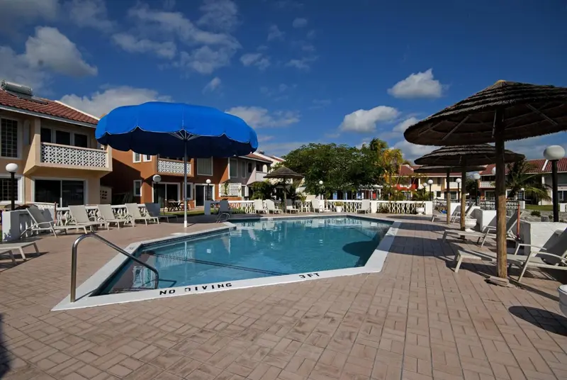 Une piscine rectangulaire bordée de chaises longues et d'ombrelles.