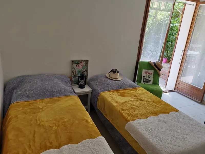 Deux lits simples avec couvertures colorées dans une pièce lumineuse.