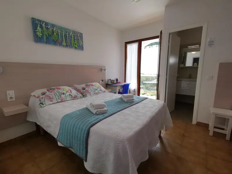 Une chambre lumineuse avec un grand lit recouvert d'une courtepointe bleue.