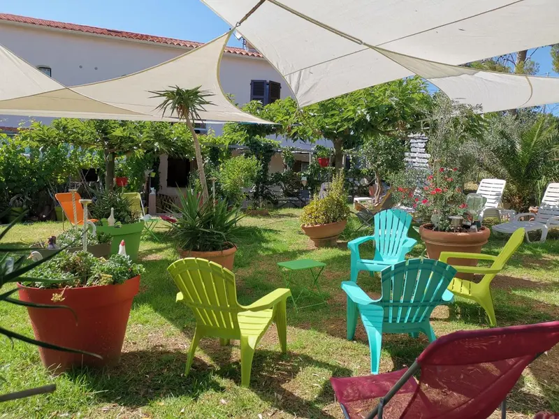 Jardin fleuri avec des chaises colorées et des parasols.
