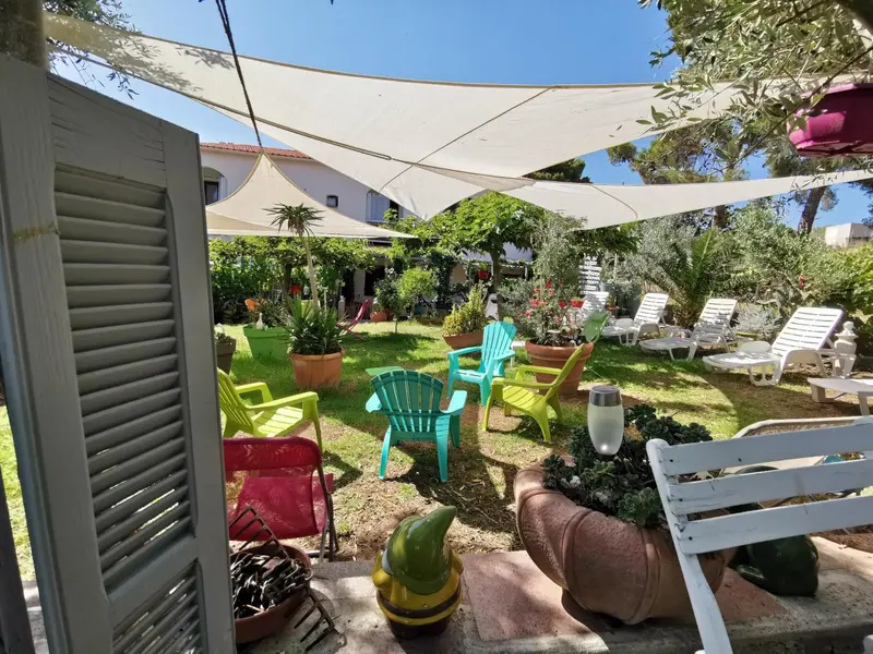 Espace extérieur aménagé avec des chaises longues et des tables colorées sous un auvent.