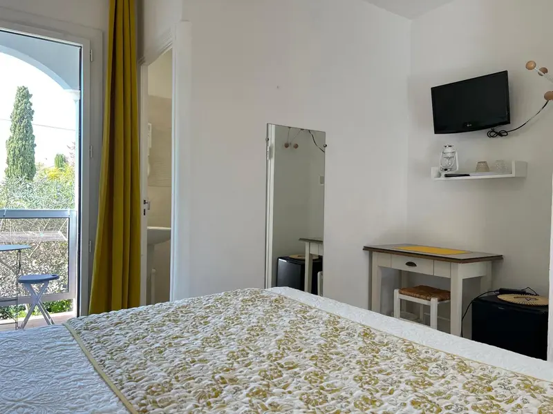 Une chambre lumineuse avec un lit recouvert d'une courtepointe et un accès à un balcon.