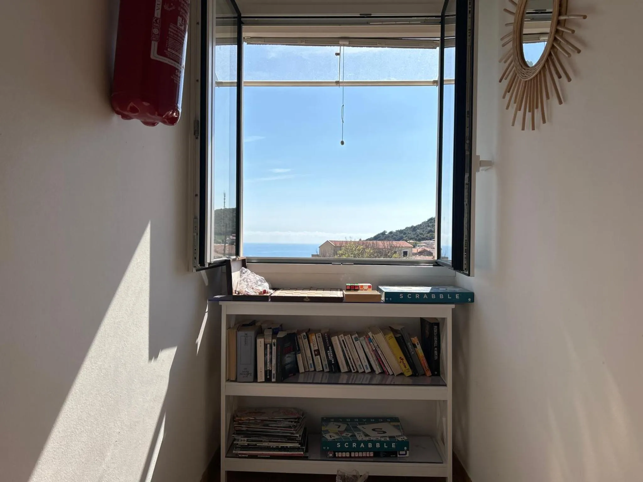 Vue sur la mer depuis une fenêtre avec une bibliothèque.