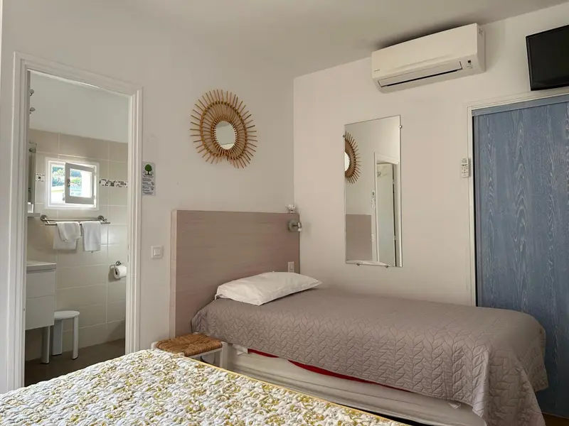 Une chambre lumineuse avec un lit simple et un accès à une salle de bain.