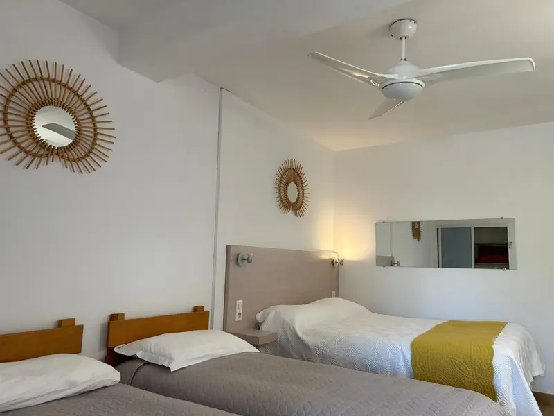 Une chambre lumineuse avec deux lits simples et des miroirs muraux.