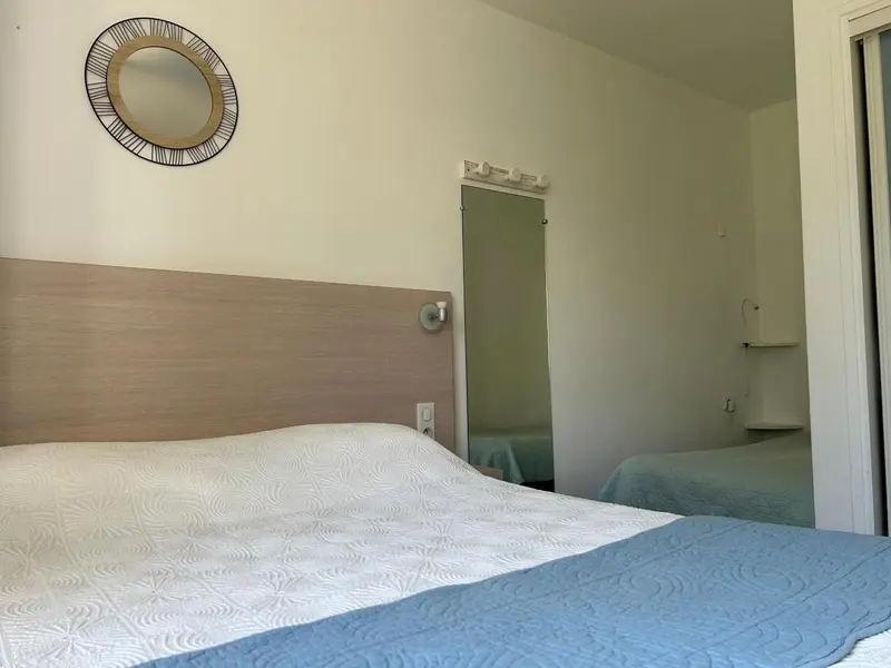 Une chambre lumineuse avec un grand lit recouvert d'une couette blanche et bleue.
