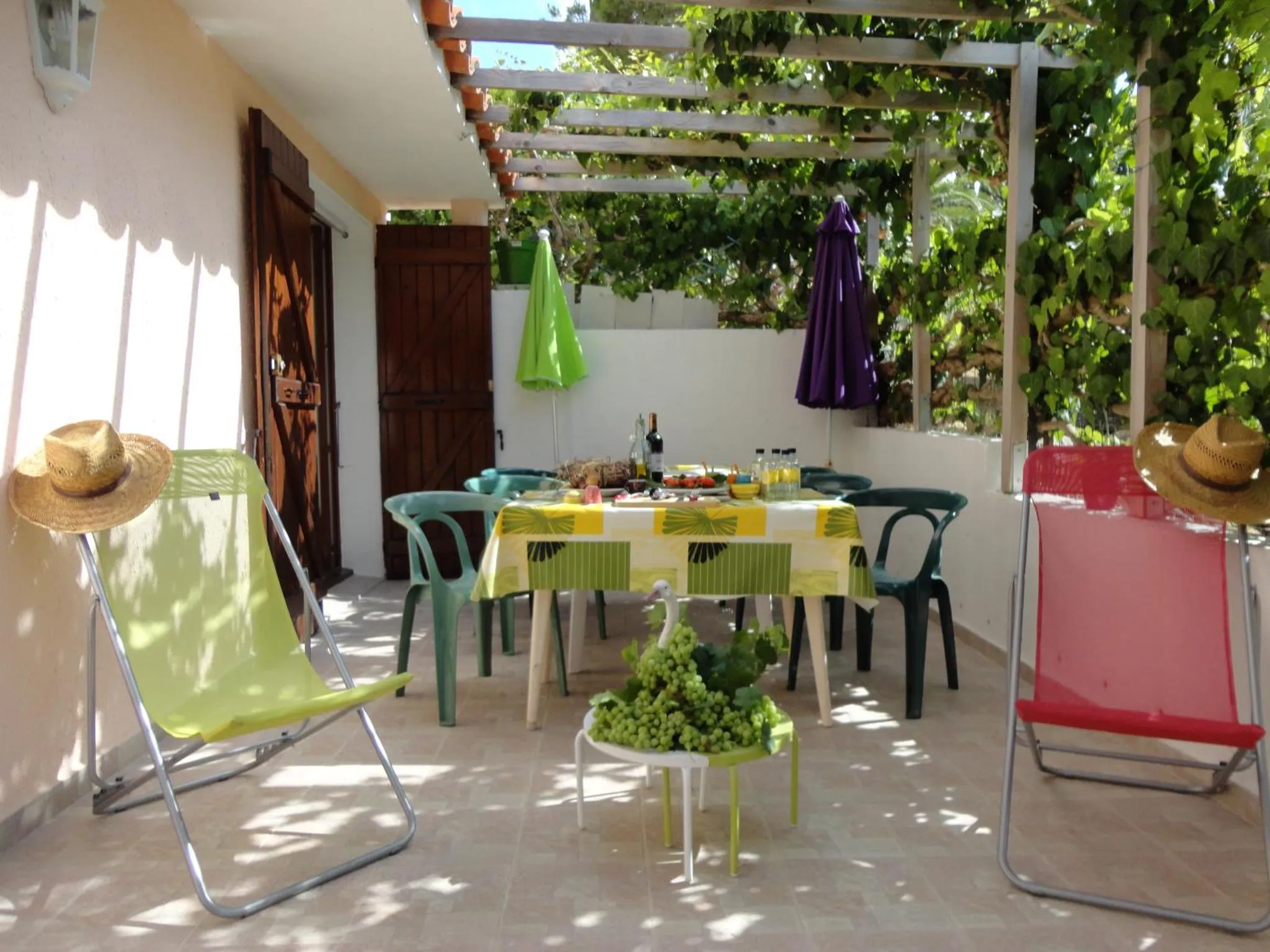 Une table colorée est mise en scène sur une terrasse ombragée.