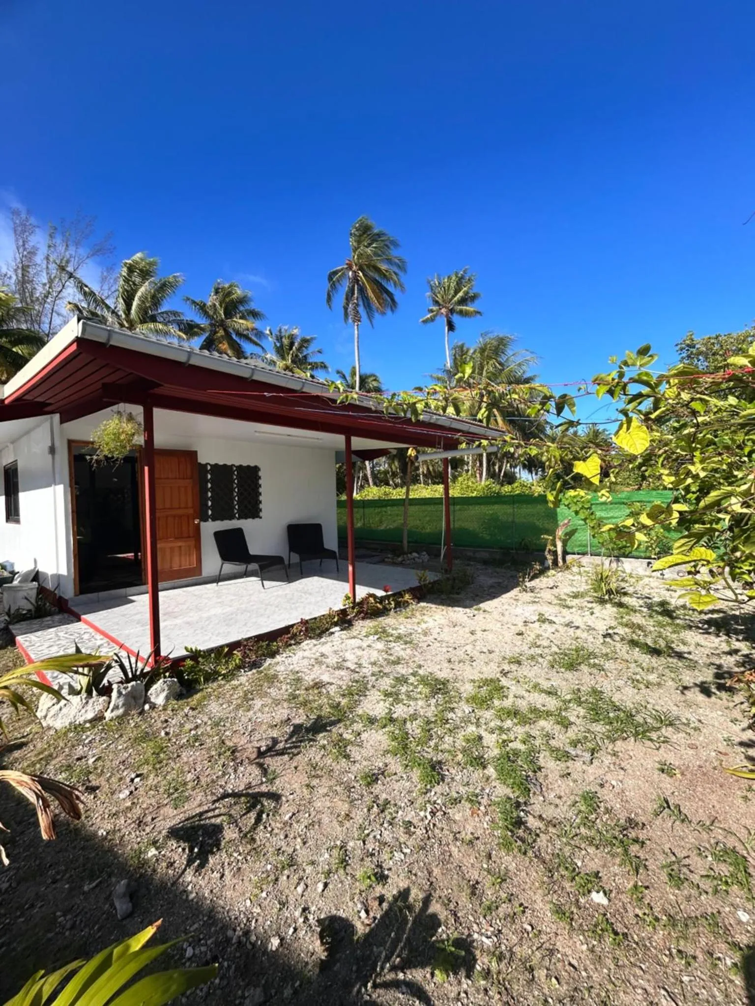 Une terrasse ombragée donne sur un jardin tropical luxuriant.