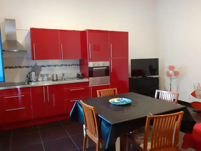 Une cuisine rouge moderne s'ouvre sur une table à manger.