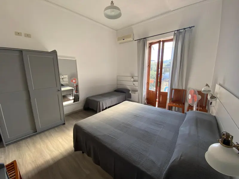 Une chambre lumineuse avec un lit double et un lit simple près d'une fenêtre.