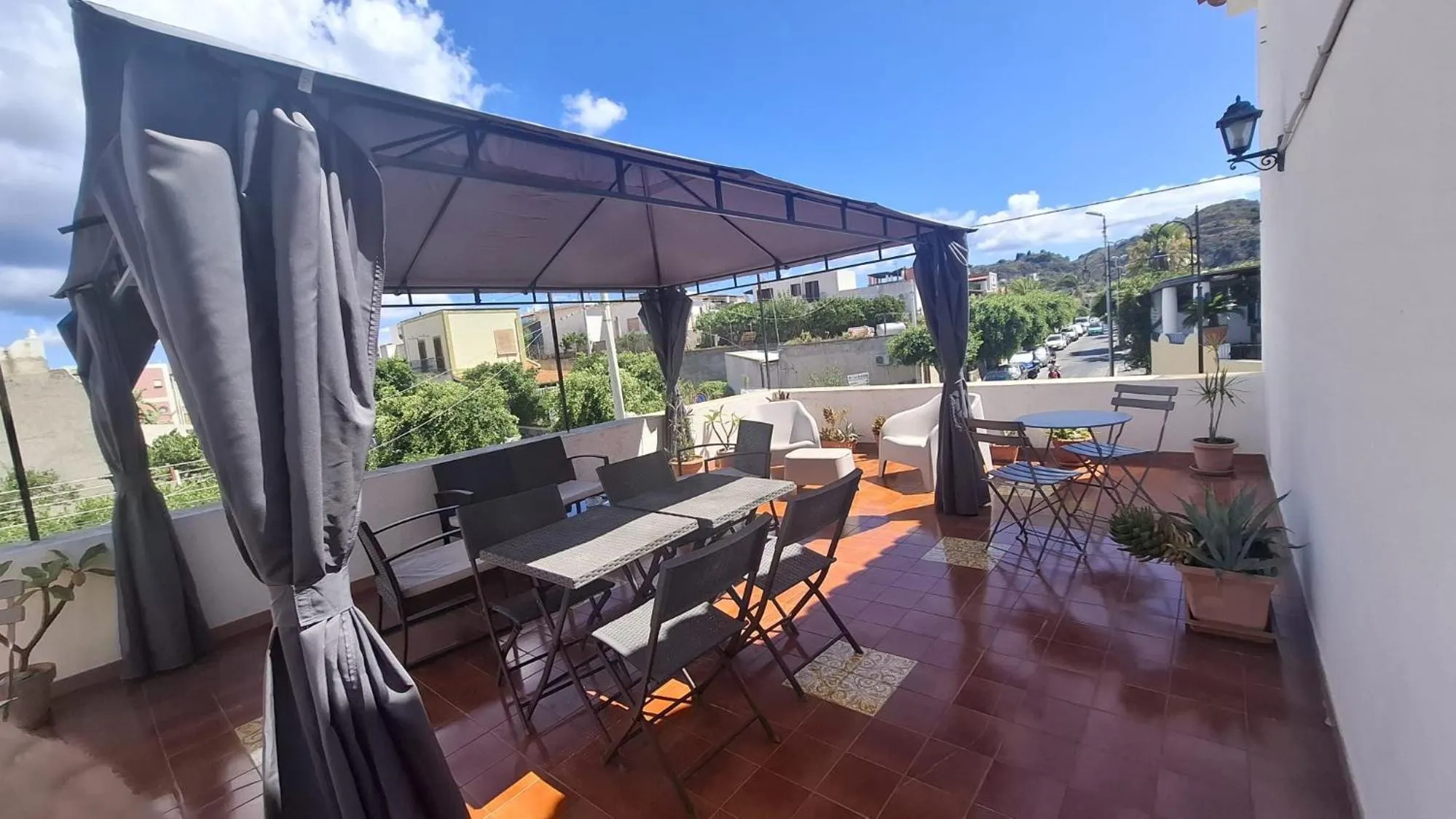 Terrasse ombragée avec tables et chaises pour les repas.