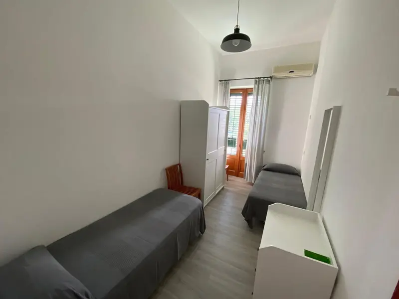 Une chambre avec deux lits simples et une armoire.