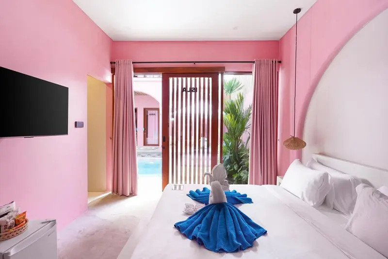 Une chambre à coucher lumineuse avec un lit blanc et des rideaux roses.